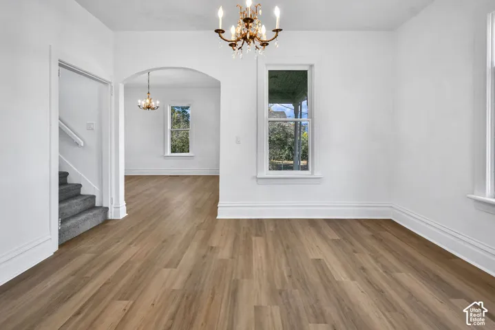 Interior space featuring wood-finish flooring, an arched entryway, double-tier candelabra light fixtures, and single-hung windows