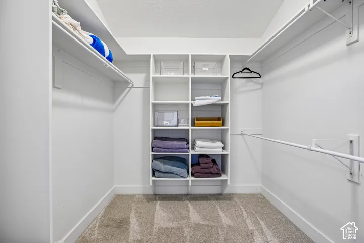 Walk-in closet featuring white built-in shelving and dual-level hanging rods