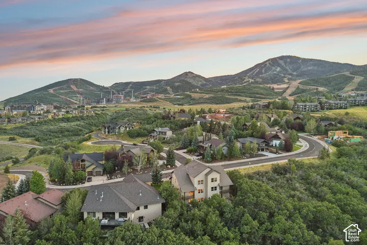 Aerial perspective featuring residential lots nestled within mature native vegetation, expansive mountainous topography, and multi-level architectural exteriors with neutral-toned siding and pitched roofing