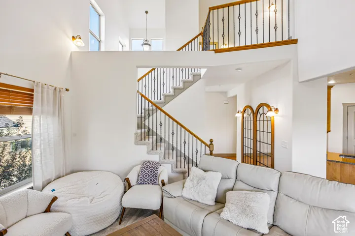 Two-story foyer featuring a vaulted ceiling, staircase with ornate metal balusters and wood handrails, mezzanine overlook, and arched wood-trimmed decorative accents