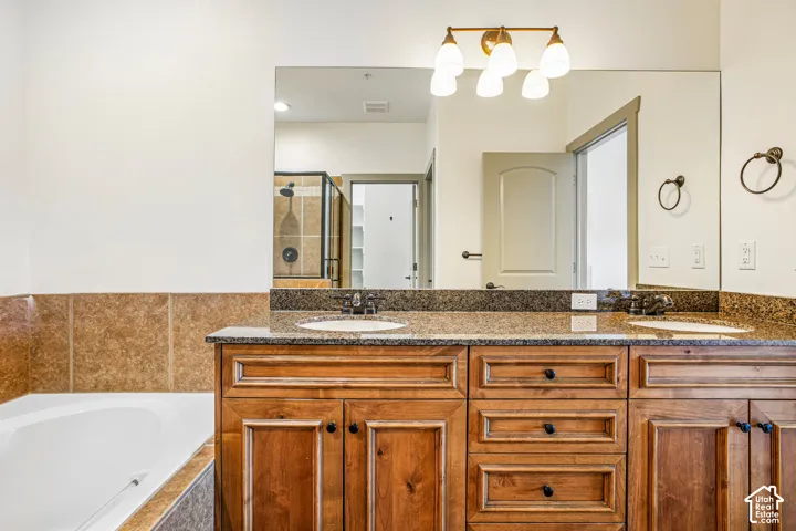Double-sink vanity featuring stained wood cabinetry, stone countertops, integrated oval basins, and five-light vanity fixture