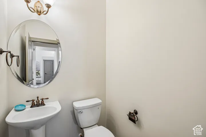 Oval wall-mounted mirror, pedestal sink, oil-rubbed bronze faucet, coordinating hardware, and dual-arm decorative light fixture