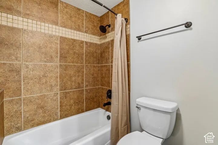 Bathtub enclosure featuring large-format ceramic wall tile, decorative mosaic tile accents, and matte black plumbing fixtures