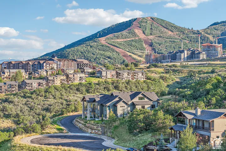 Mountainous backdrop featuring high-altitude terrain, multi-level residential architecture, natural landscape, and paved cul-de-sac