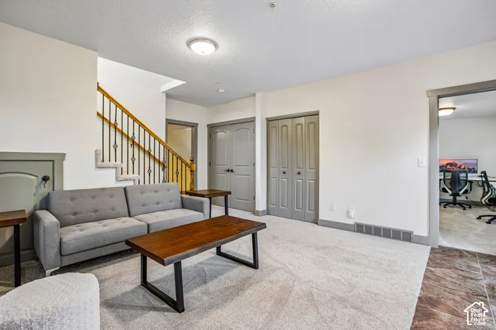 Interior space featuring neutral-toned carpeting, staircase with metal balusters, paneled interior doors, and overhead flush-mount lighting
