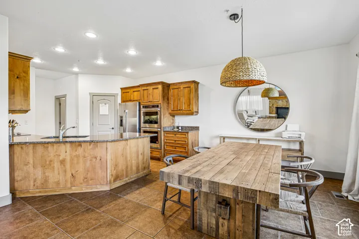 Kitchen featuring wood cabinetry, stone-surface countertops, built-in double wall ovens, recessed lighting, and tile flooring