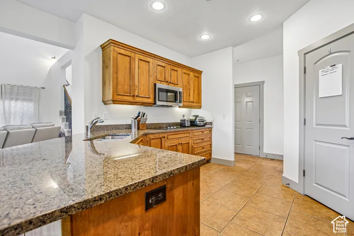 Kitchen featuring wood cabinetry, stone-surface countertops, tile flooring, and recessed ceiling lighting