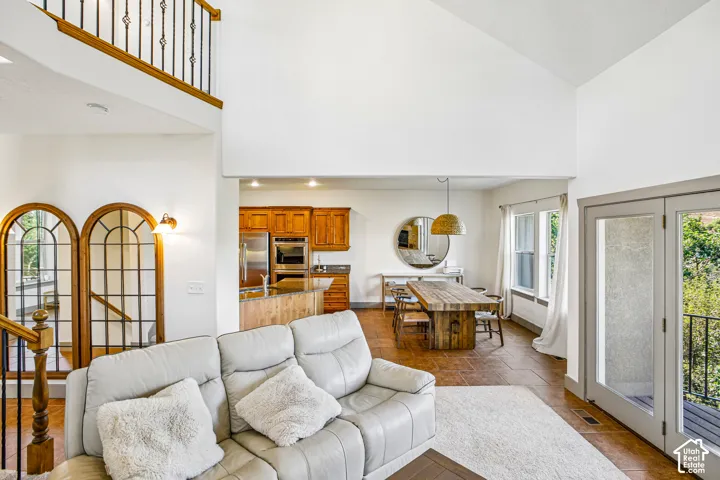 Vaulted ceiling, interior balcony with ornamental wrought iron railing, arched glass-panel room dividers, built-in cabinetry, and tile flooring