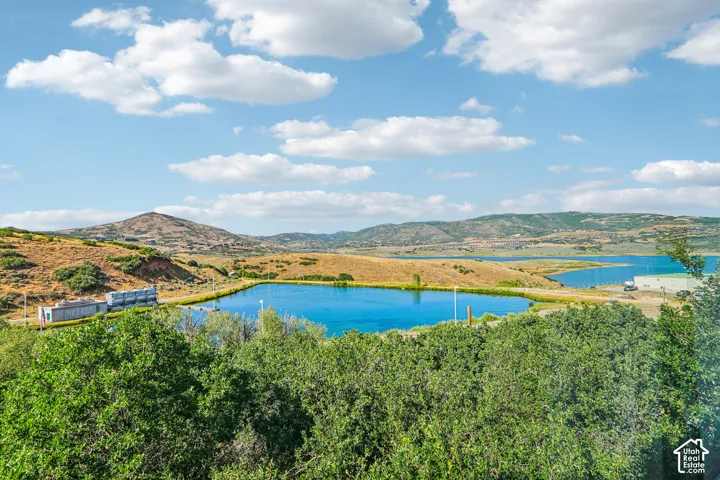Expansive landscape featuring a large water reservoir, rolling hills, and mature trees
