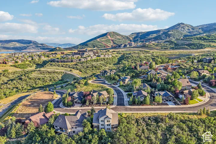 Aerial perspective of a hillside residential community featuring multi-story dwellings, paved roadways, and surrounding mountain scenery
