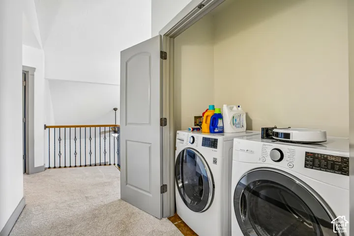 Laundry closet with interior hookups, featuring a paneled door, metal baluster railing, and wall-to-wall carpeting