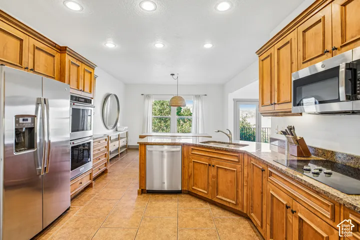 Kitchen featuring natural wood cabinetry, stone-finish countertops, stainless steel appliances, a built-in double oven, and recessed lighting