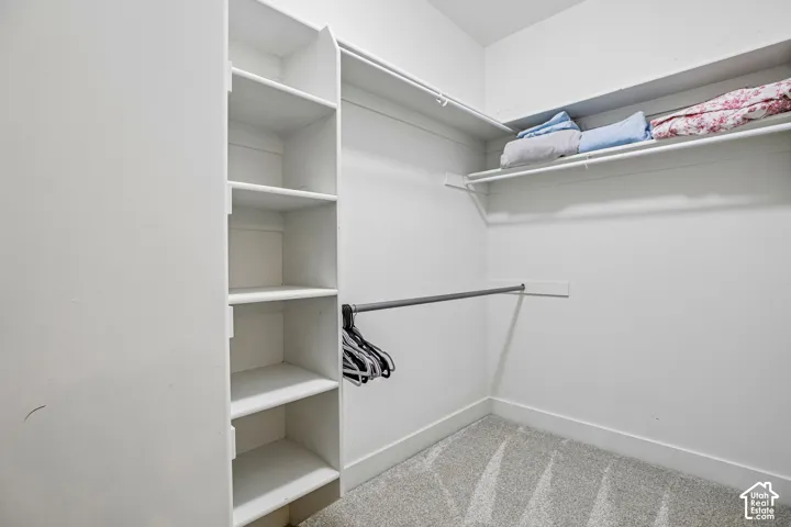 Walk-in closet featuring built-in vertical shelving, integrated clothing rods, and overhead storage ledges