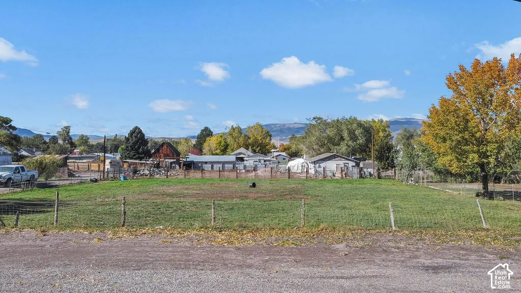 Open, level parcel enclosed by wire fencing with mature trees and mountain scenery