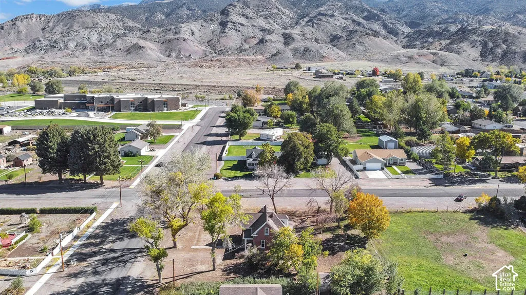 Aerial perspective featuring a multi-story residence with a pitched roof, mature trees, and prominent mountain backdrop