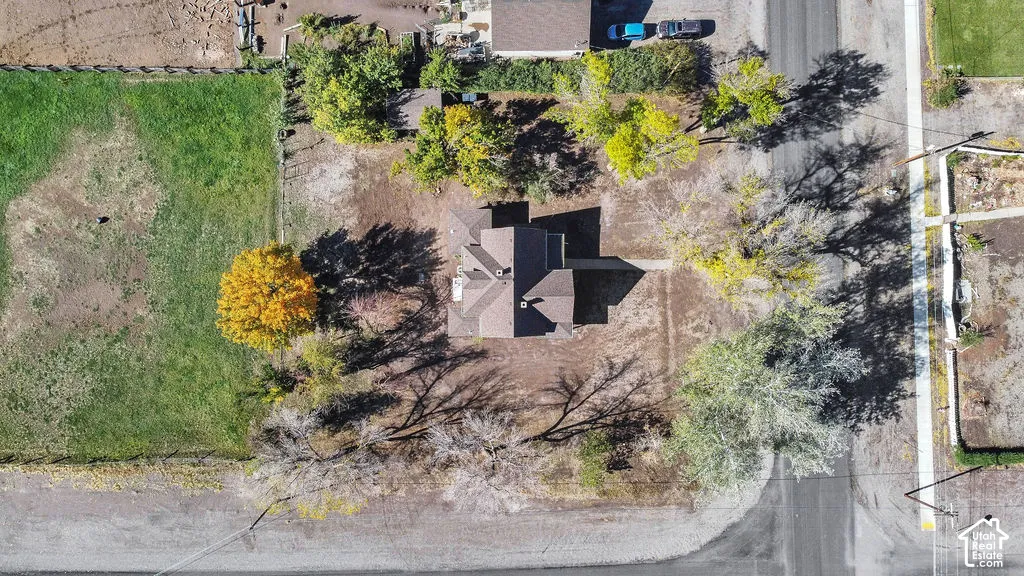 Aerial perspective of a detached residence featuring a pitched roof, expansive lot, established trees, and perimeter fencing