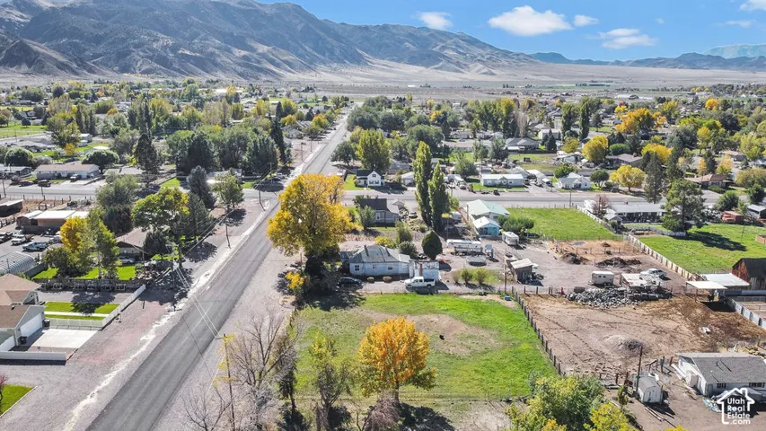 Aerial perspective of property featuring expansive acreage, mature trees, and prominent mountain backdrop