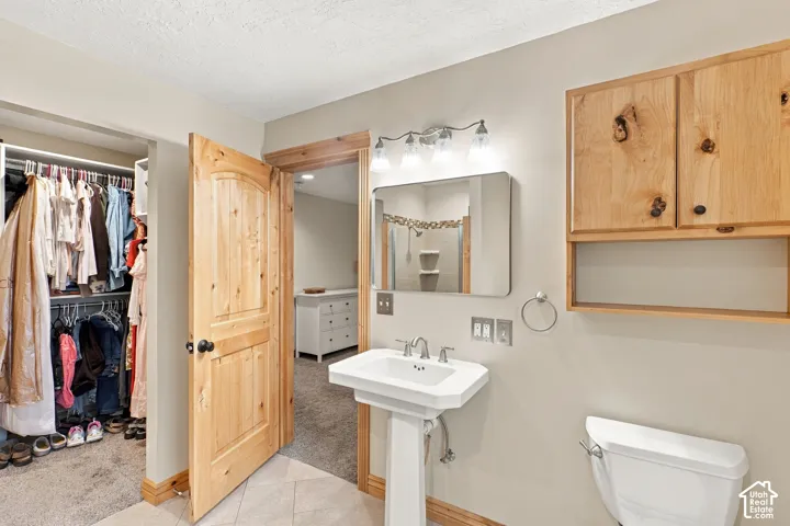 White pedestal sink with chrome faucet, wall-mounted natural wood cabinetry, and solid wood interior door with matching wood trim