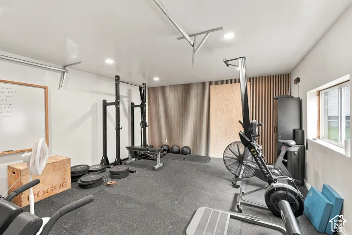 Multi-purpose room featuring recessed lighting, rubberized flooring, vertical wood-slat wall paneling, and a natural wood-finish accent door