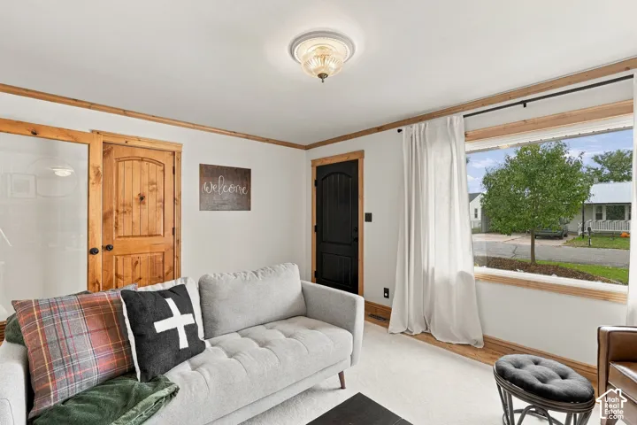Interior space featuring a large picture window with natural wood trim, natural wood door casing, a contrasting black door, and a flush-mount glass light fixture