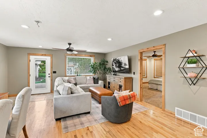 Living area featuring wood-finish flooring, recessed lighting, natural wood trim, and a full-light glass door