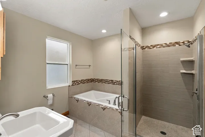 Bathroom featuring a soaking tub with tile surround, glass-enclosed shower with tiled walls, built-in shelving, mosaic tile accents, and recessed lighting