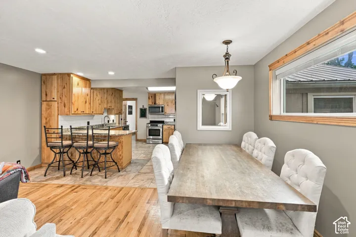 Kitchen featuring knotty wood cabinetry, stone countertops, stainless steel appliances, wood-finish flooring, and a pendant light fixture