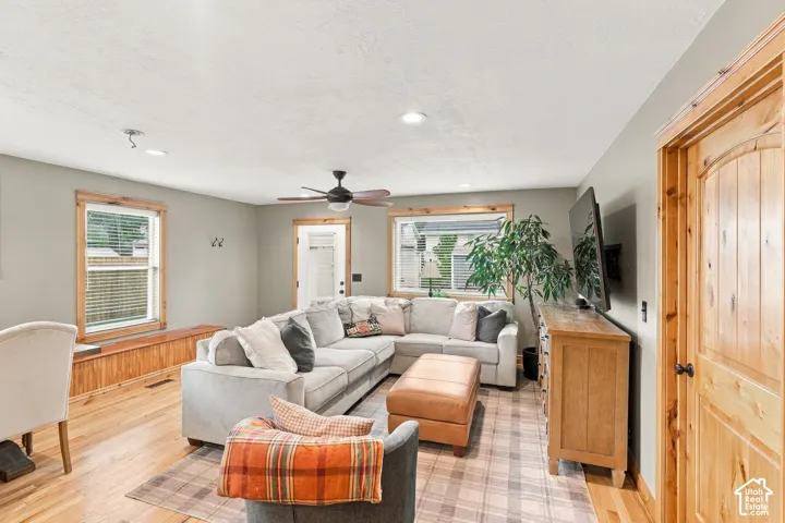 Living area featuring natural wood-finish flooring, recessed lighting, a ceiling fan, a custom built-in window bench with wood trim, and natural wood door casings