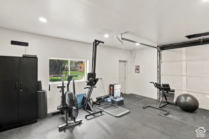Garage space featuring recessed ceiling lighting, a single-pane sliding window, and rubberized flooring