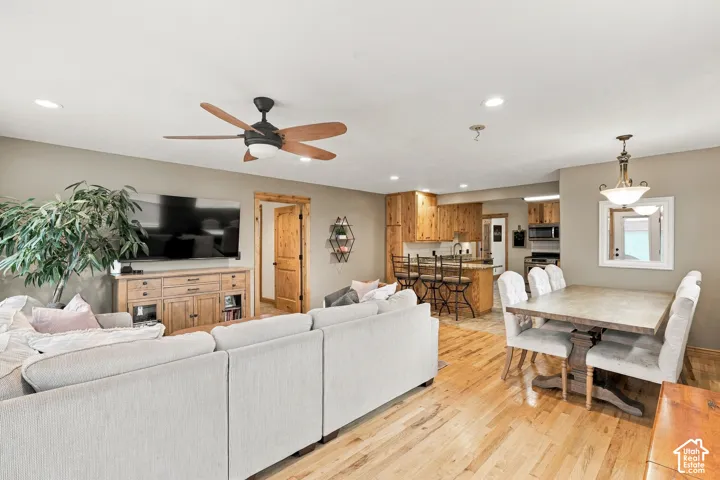 Open-concept main living area featuring natural wood-finish flooring, knotty pine cabinetry, recessed lighting, and a ceiling fan with integrated lighting