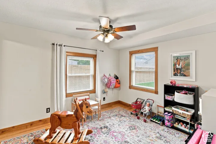 Room interior featuring dual-pane windows with natural wood trim, multi-speed ceiling fan with integrated lighting, and neutral wall tones