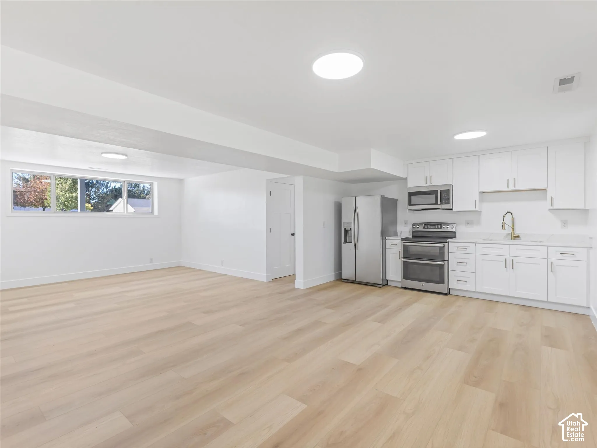 Second Kitchen area featuring white shaker-style cabinetry, stainless steel appliances, wood-finish flooring, and recessed ceiling lighting