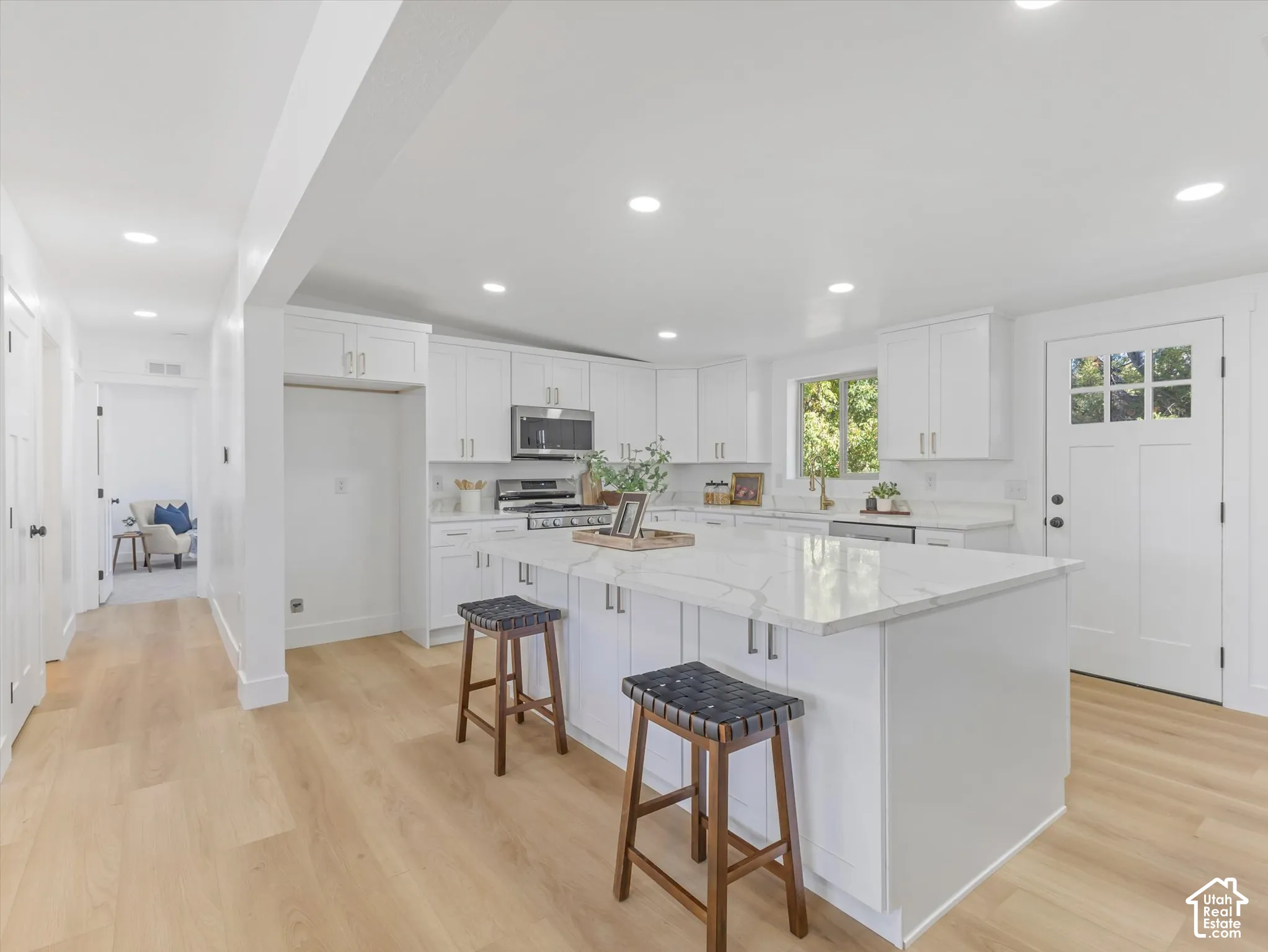 Kitchen featuring a spacious central island with a stone-finish countertop, white cabinetry, integrated recessed lighting, and wood-finish flooring