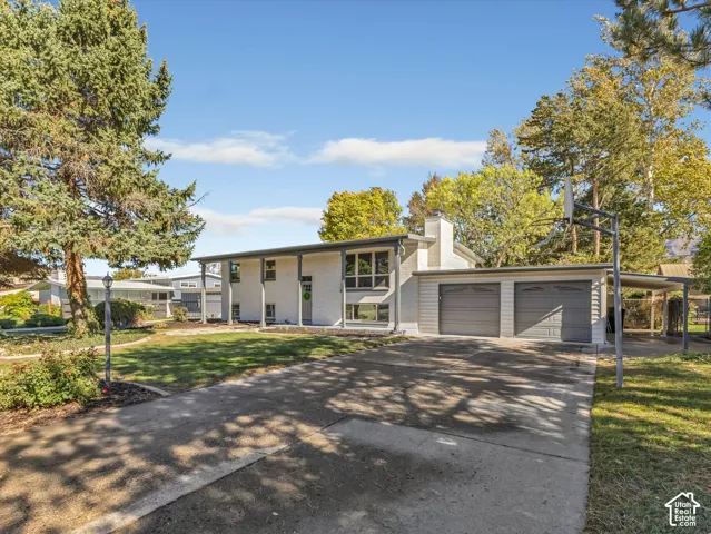 Split-level exterior featuring a stucco facade, covered front porch, two-car garage, and concrete driveway