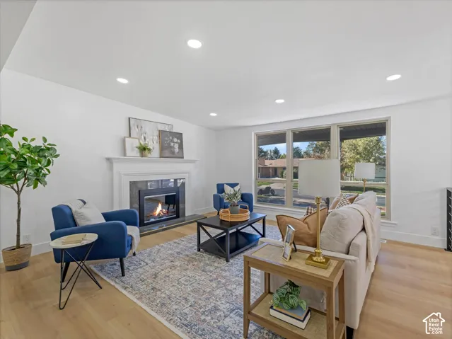 Living area featuring recessed lighting, light-tone wood-finish flooring, and a fireplace with a decorative mantel and stone surround