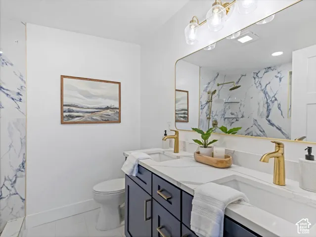 Master Bathroom featuring a dual-sink vanity with quartz countertop, brass-finish fixtures, a large wall-mounted mirror, and Huge tile shower with bench.