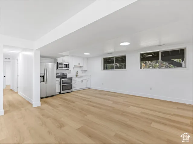 Kitchen featuring white cabinetry, stainless steel appliances, wood-finish flooring, and recessed lighting