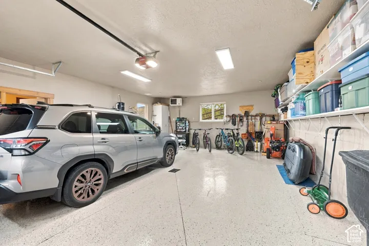 Attached two-car garage featuring epoxy-finished flooring, overhead fluorescent lighting, built-in wall shelving, and an automated garage door opener
