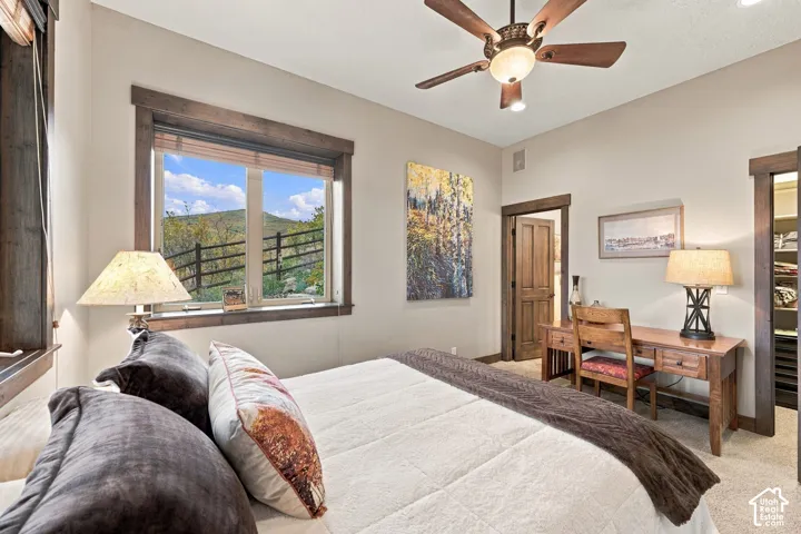 Bedroom featuring wood-trimmed windows, a ceiling fan with integrated lighting, door casing with matching wood finishes, and neutral wall-to-wall carpeting