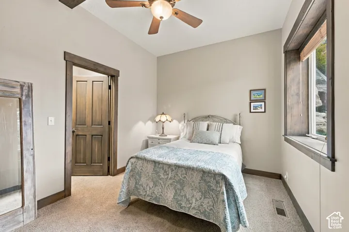 Room featuring medium-tone stained wood door and window casing, neutral wall color, carpeted flooring, and a ceiling fan with integrated lighting