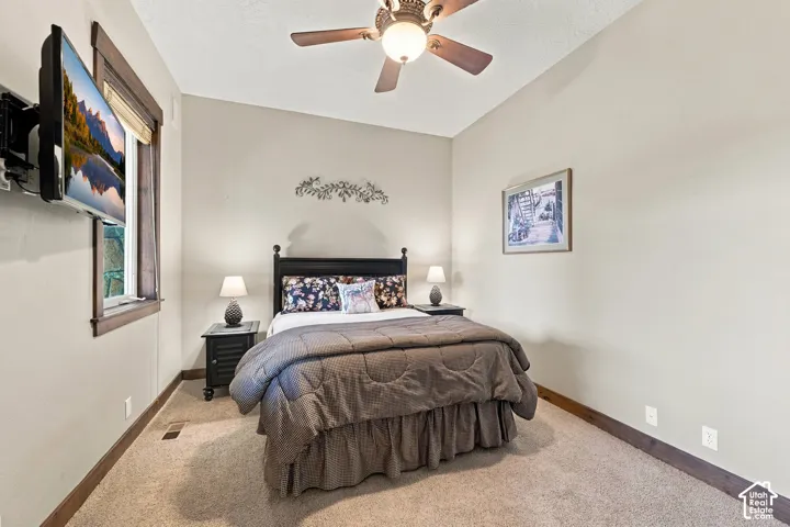 Neutral-toned room featuring a ceiling fan with light fixture and stained-wood window trim