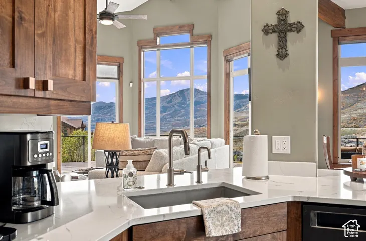 Kitchen featuring solid surface countertops, an undermount sink with a gooseneck faucet, stained wood cabinetry, and large windows with mountain scenery