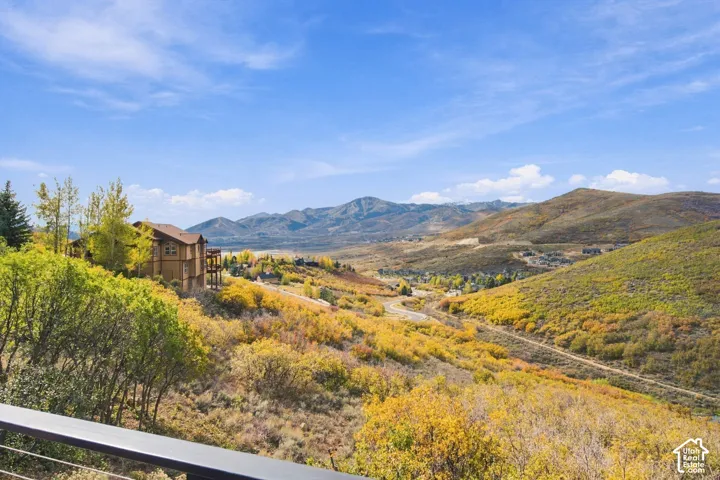Multi-story residence featuring wood and stone exterior siding, elevated deck with cable railing, and expansive mountain scenery