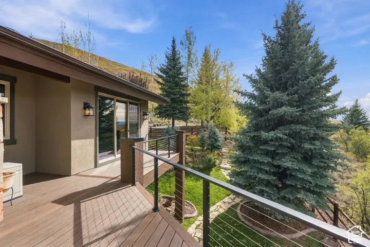 Elevated deck featuring composite wood-finish decking, cable railings, and exterior wall-mounted lighting