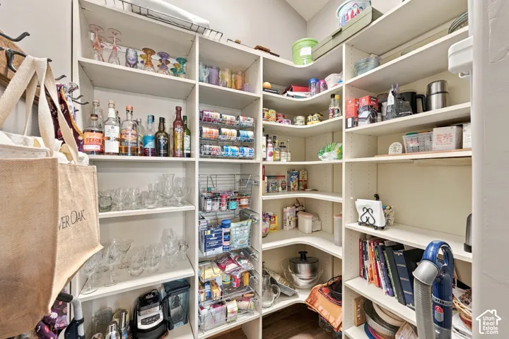 Walk-in storage pantry featuring white floor-to-ceiling shelving, corner shelving units, and integrated wire pull-out baskets