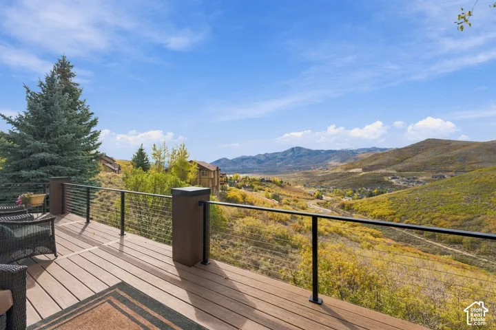 Elevated deck featuring composite decking, cable railing, and solid pillars, overlooking mountainous terrain