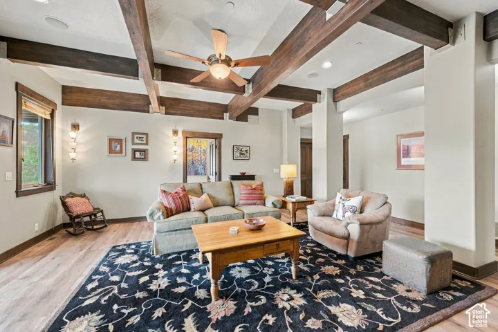 Exposed dark wood ceiling beams, wood-finish flooring, recessed lighting, and wall-mounted sconces