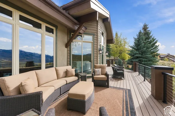 Expansive elevated deck featuring composite decking, metal cable railing, structural timber accents, and wall-mounted exterior lighting