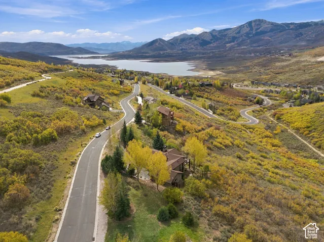 Aerial perspective of a hillside property featuring mountain topography, native vegetation, and surrounding lake scenery
