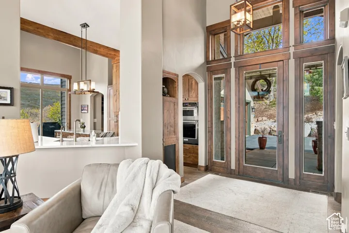 Grand entryway featuring wood-trimmed glass entry doors, soaring ceilings, natural stone flooring, custom wood-framed transom windows, and built-in cabinetry